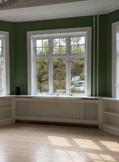Indbyggede reoler på hver side af radiator under stort vinduesparti