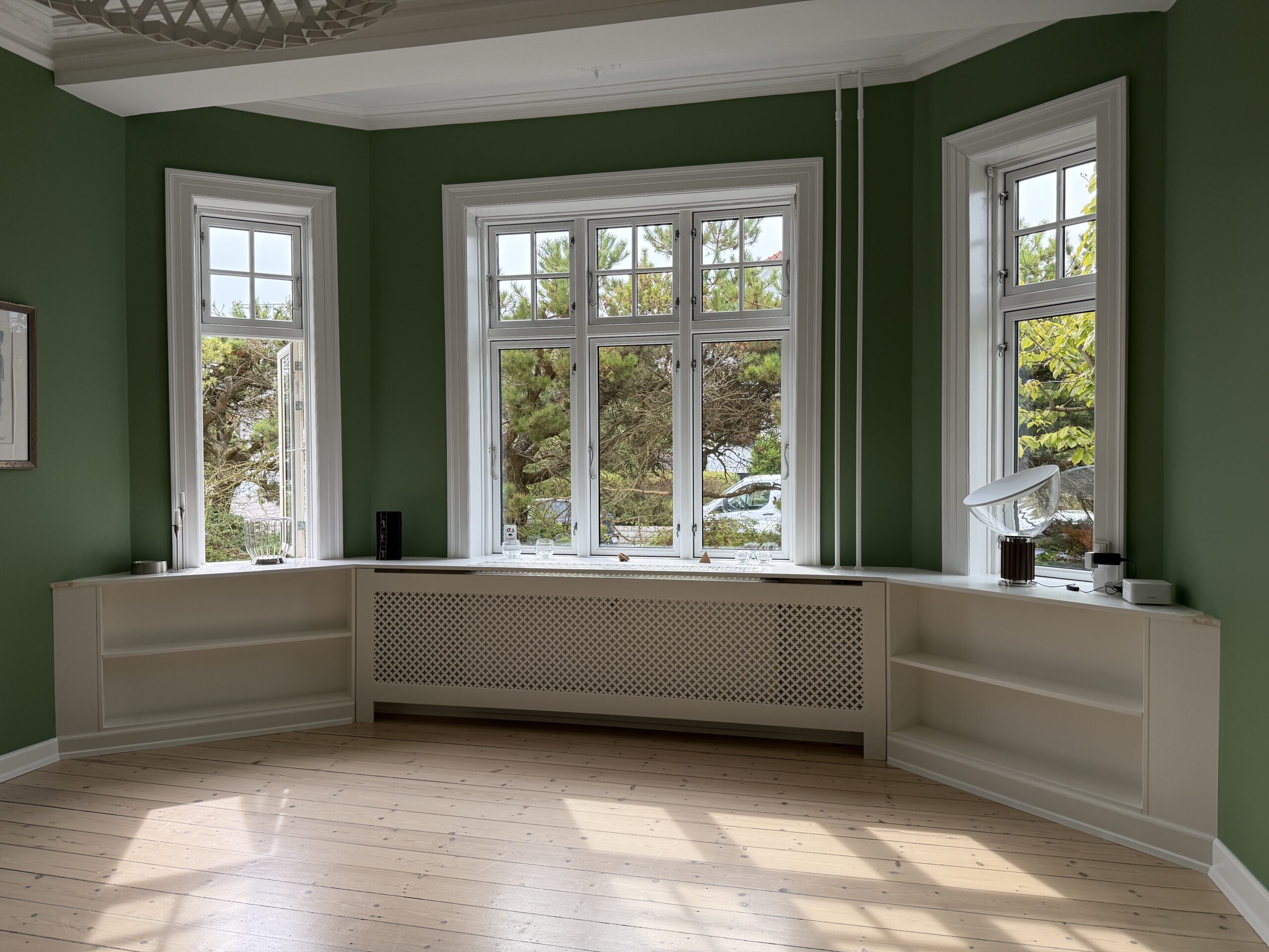 Indbyggede reoler på hver side af radiator under stort vinduesparti