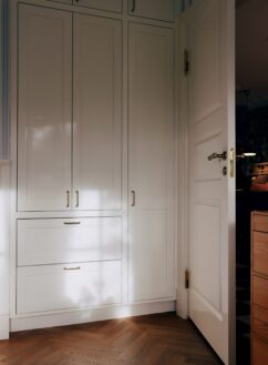 Hvid indbygget garderobe med fyldningslåger og messinggreb